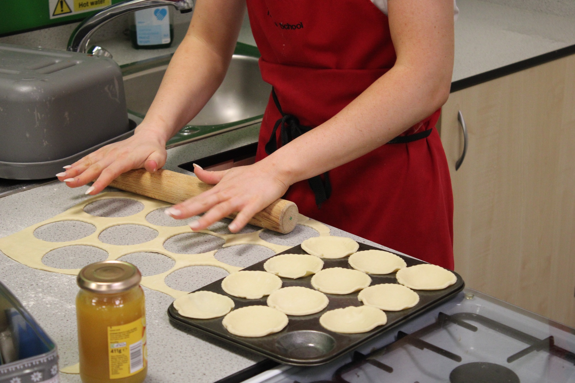 A student preparing jam tarts in their food lesson.